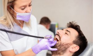The dentist cleanses the mouth of the patient.