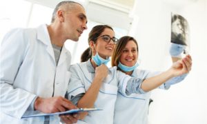 A group of friendly dentists discussing about possible tooth replacement options for a patient.